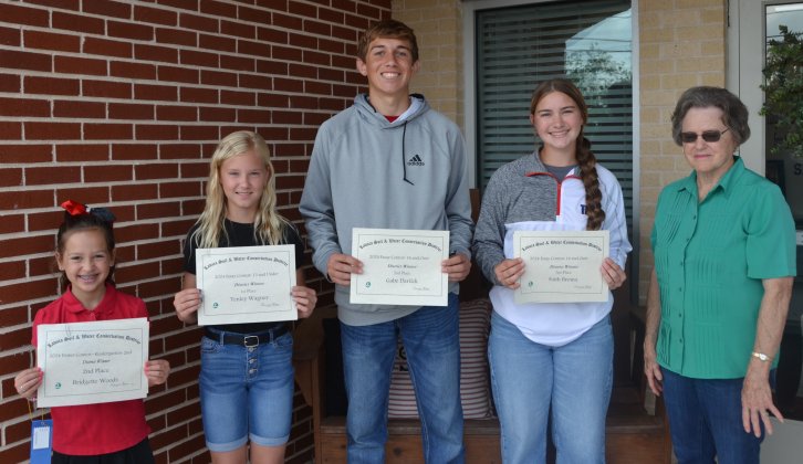 Shiner Catholic Schools had four students place in the Lavaca Soil and Water Conservation District poster and essay contest. From left are Bridgette Woods, whose poster placed second in district in the K-2nd division, Tenley Wagner, whose essay placed first in the 13 and under division, Gabe Darilek, whose essay placed second in the 14 and over division, Faith Brown, whose essay placed third in the 14 and over divisions, and LSWCD secretary Dorothy Henke. Photo by Jimmy Appelt