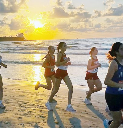 Emma Marshall (middle) and Faith Brown (right) run on the beach with the sunrise as a picturesque background during the Port Aransas Invitational on Saturday. Photo courtesy of Nicco Brown.