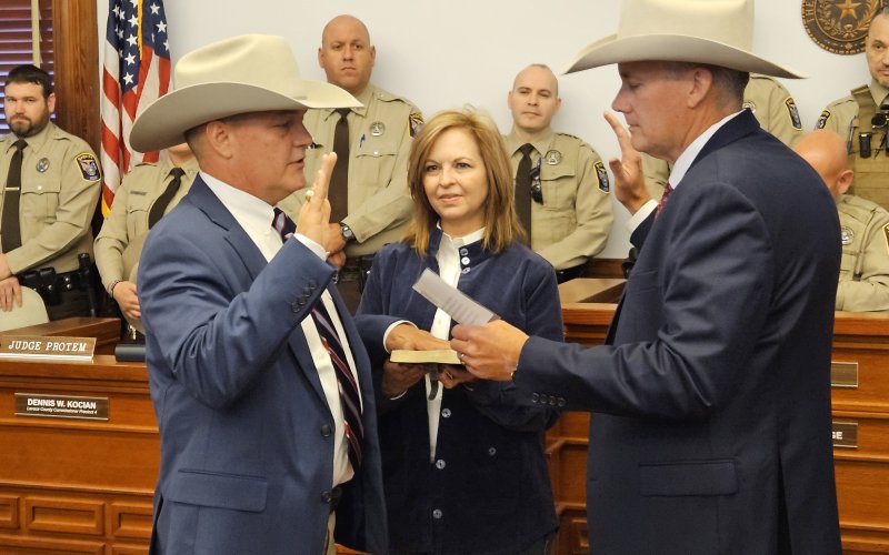 With wife Kim at his holding a Bible he was given by a fellow law enforcement officer 19 Christmases ago, Steven Greenwell accepts his oath of office in a ceremony led by Goliad County Sheriff Roy Boyd. Photo by Bobby Horecka