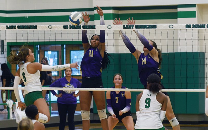Kiera Curtis (#11) and Kayden Smith (#14) leap up to block a hit from Cuero’s Taylor Gayle Thursday morning in the Cuero Tournament. Shiner won five of eight games and placed third in the tournament. Photo by Mark Lube.