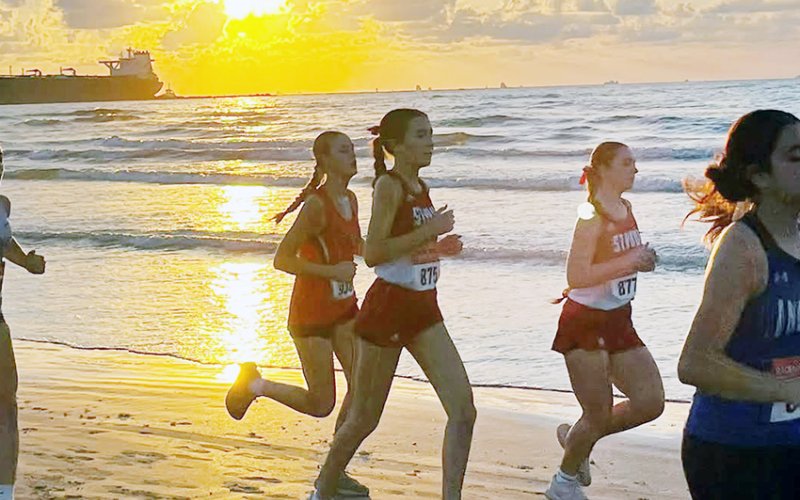 Emma Marshall (middle) and Faith Brown (right) run on the beach with the sunrise as a picturesque background during the Port Aransas Invitational on Saturday. Photo courtesy of Nicco Brown.