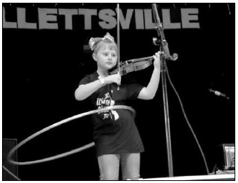 Photo by Hans Lammeman McKenna Peterson focuses while playing a melody on her fiddle and balancing a Hula-Hoop at the 51st annual Texas State Championship Fiddlers Frolics.