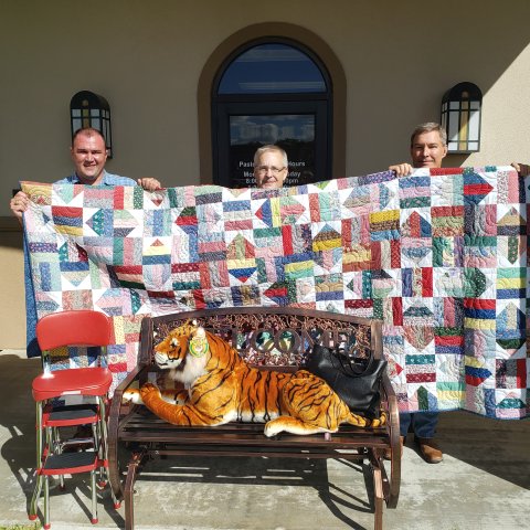  Pictured from left to right are SJS Principal Sean Mooney, Father Matthew Huehlefeld, and Picnic Chairperson Patrick Matusek with some of the auction items.