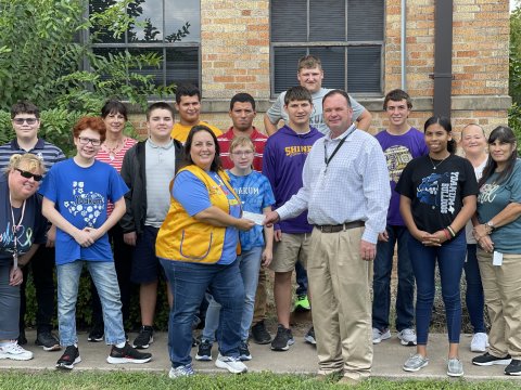 Shiner Lions Club’s Meagan Moore (front left) presents DLSEC Executive Director Jason Appelt (front right) with a donation as part of their annual support in front of Mrs. Thiry’s students and staff. Contributed Photo