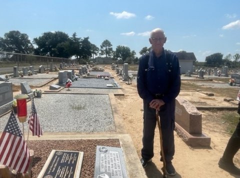 August Janak stands next to his parent’s gravestones, where a plaque was set honoring his brothers who served in the U.S. Army.