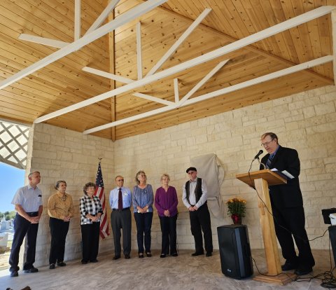 Members Ronnie Leck, Irene Cerny, Mary Ann Fojt, Larry Gerum, Suzanne Rabke, Norma Goetz and historian Doug Kubicek listen to Cemetery Association President Chuck Stratman.