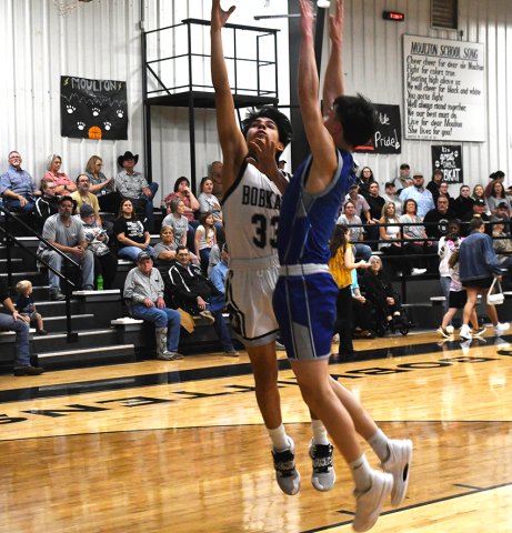 Ricky Santana tries for an inside bucket while a Waelder player plays defense. Photo by Mark Lube.