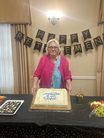 Virginia Vincik poses with her retirement cake at a party held in her honor. Photo by Clayton Kelley
