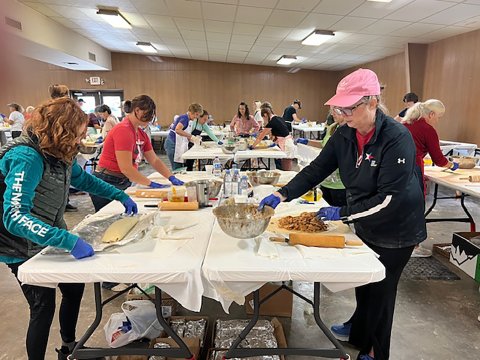 Parishioners and volunteers are shown filling and rolling up strudels.
