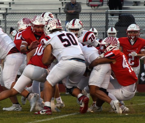 Jacob Arriola (right) starts to pull down the Lion ball carrier while several teammates rush in to help with the tackle. Photo by Mark Lube,