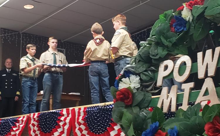 The POW/MIA wreath, of which Vietnam had more than its fair share for American troops, stands in silkent reminder while a Boy Scout troop performs a flag folding ceremony in the background during a recent Hallettsville veteran's appreciation event.